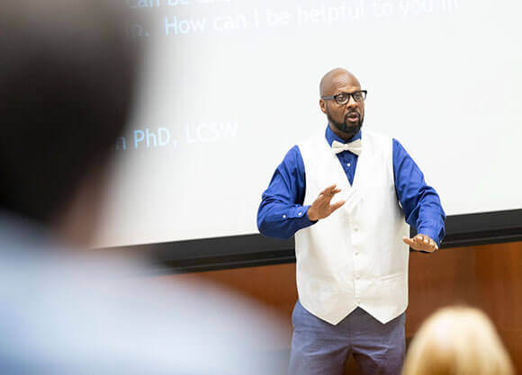 Donta Gorham stands talking in front of a crowd of people.