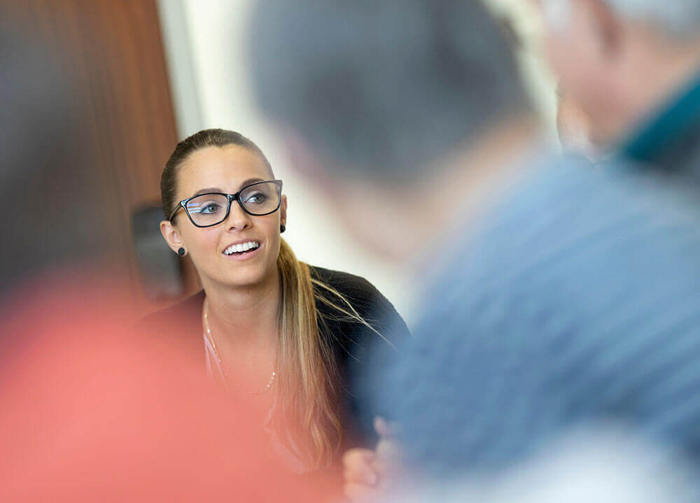 A social work student speaks with three senior citizens during a support group she directs