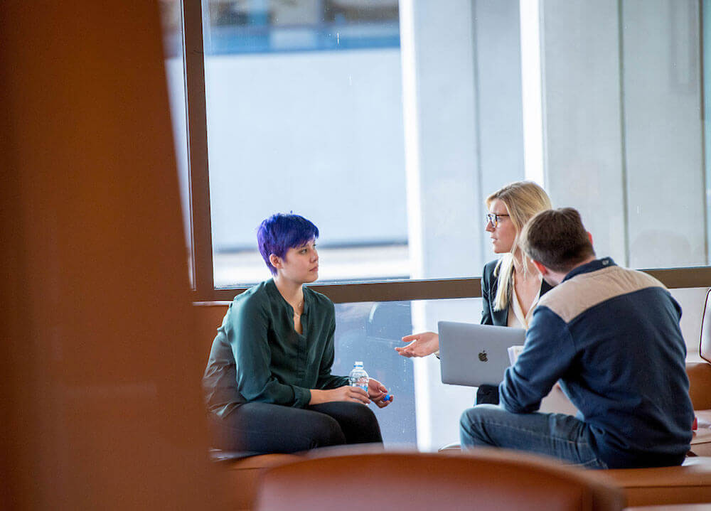 Three law students sit in a semi-circle in a study area in the School of Law